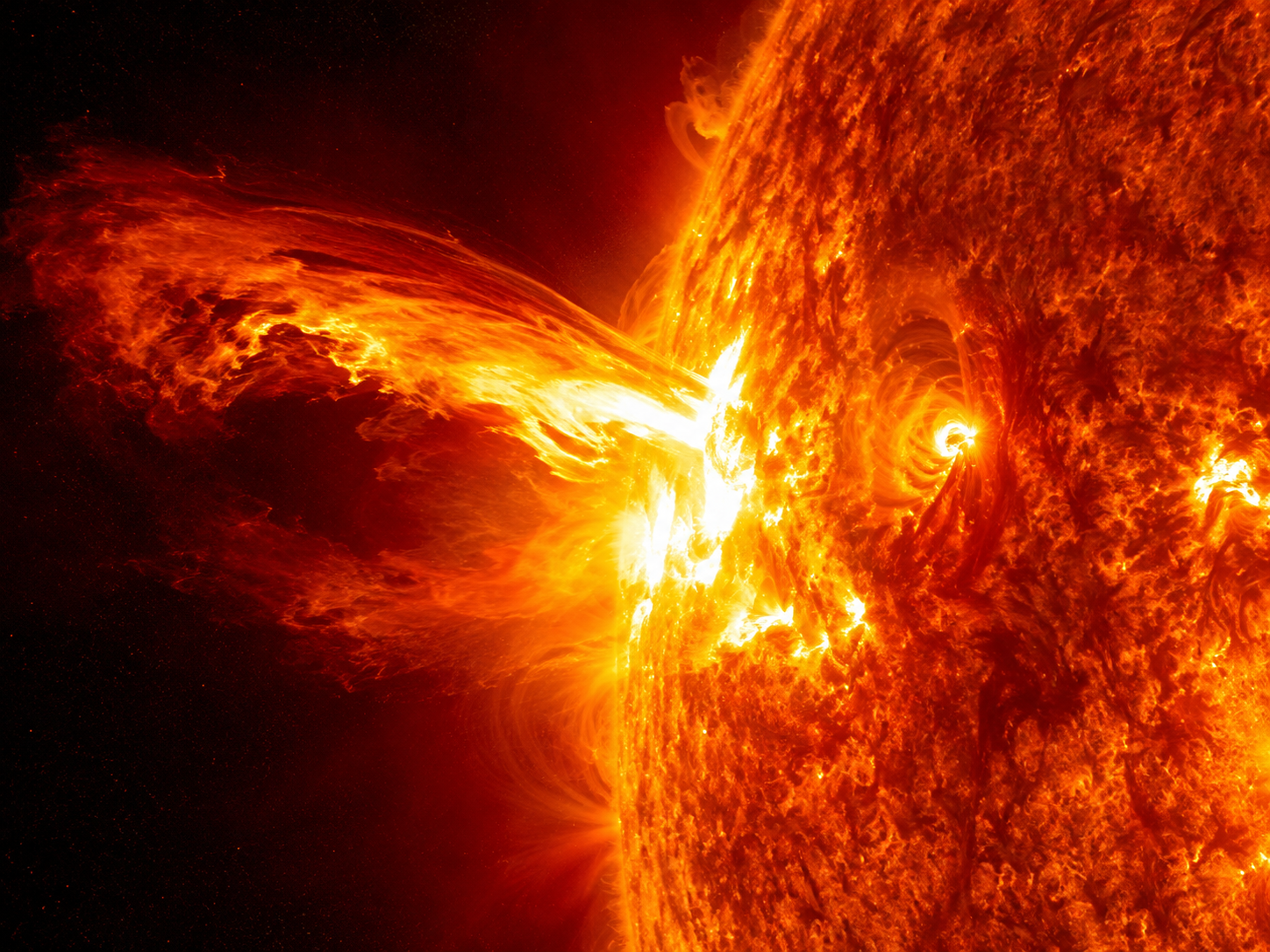 A spectacular solar flare erupting from the Sun's surface with glowing plasma extending into space.