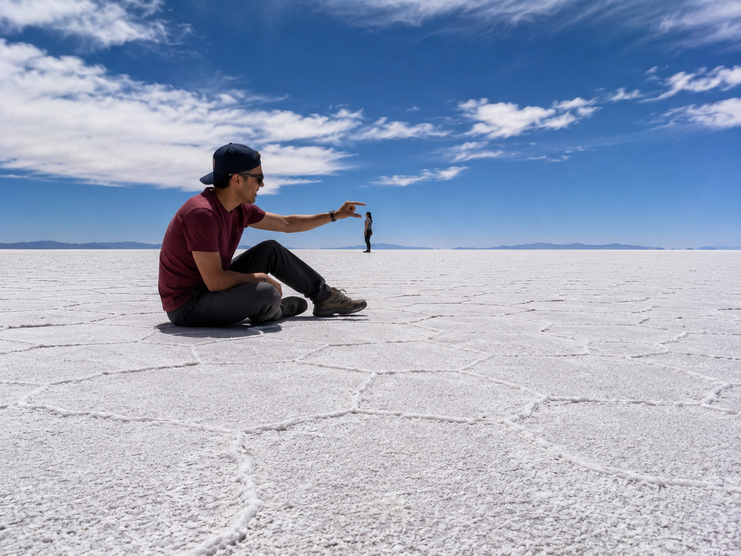 Tourist using forced perspective to create an optical illusion on the flat surface of Salar de Uyuni.