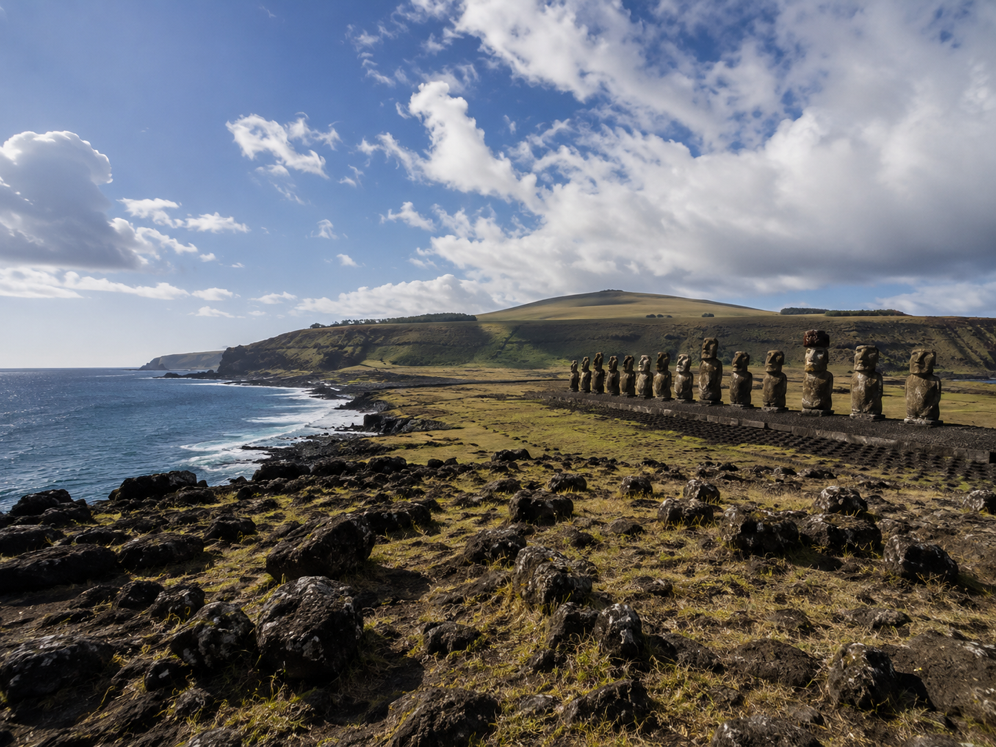 Volcanic landscape of Rapa Nui with moai and the Pacific coastline in the distance.