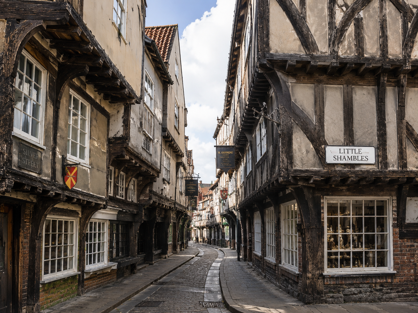 Surviving historic timber-framed houses with projecting upper floors line a narrow English town street.