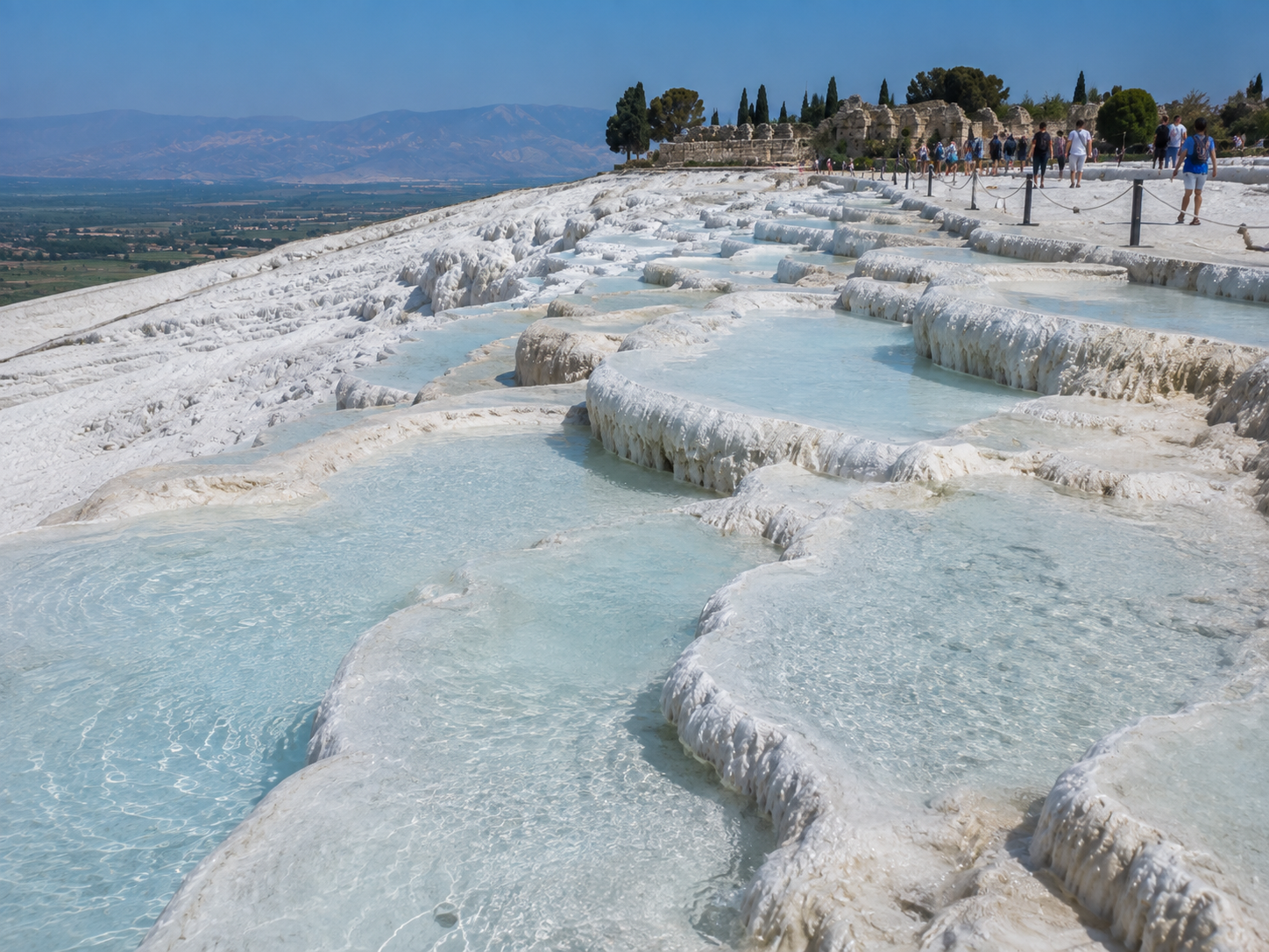 Visitors follow designated paths near protected white travertine terraces at Pamukkale.