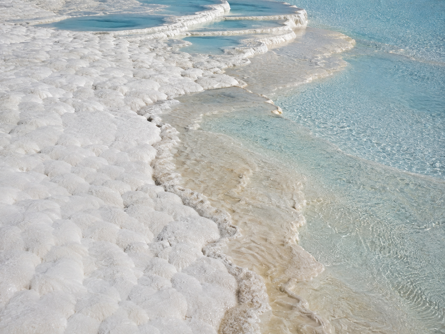 White travertine, blue thermal pools and slightly different mineral surfaces appear together at Pamukkale.