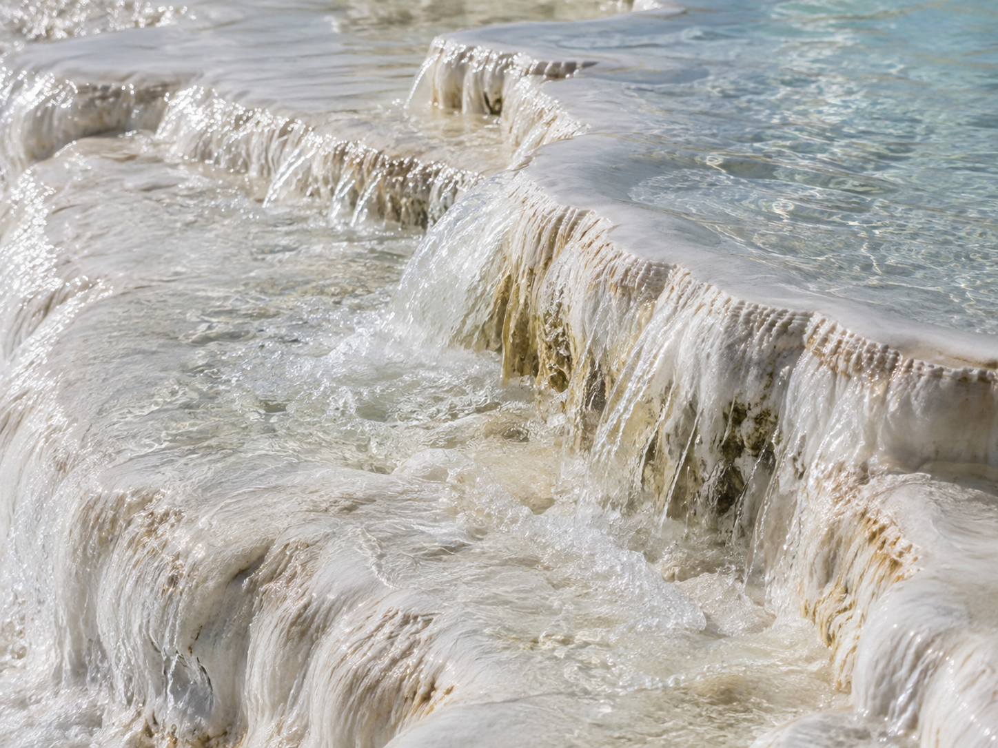 Thermal water flows over layered white travertine at Pamukkale.