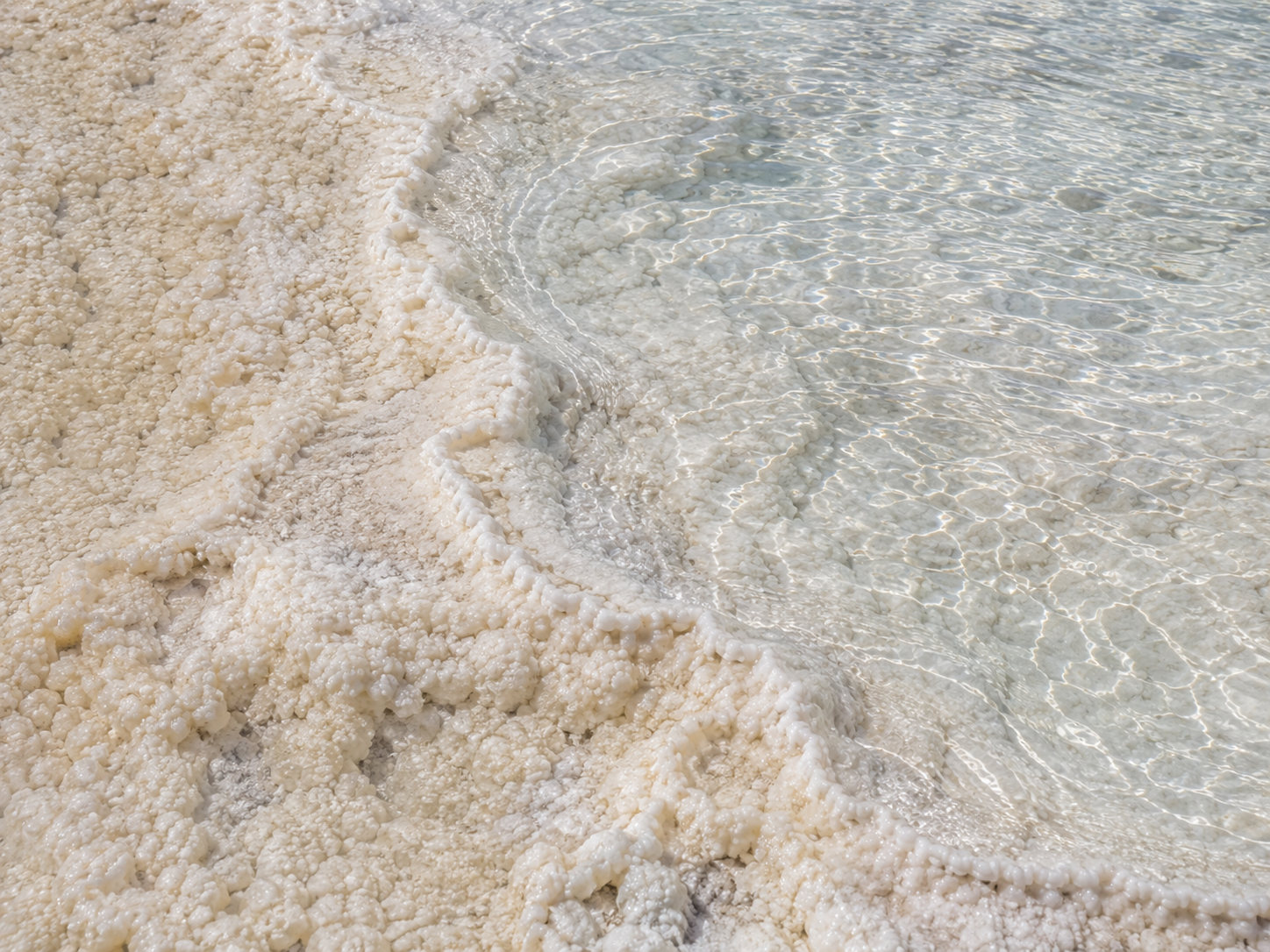 Clear thermal water leaves pale calcium carbonate deposits along the edge of Pamukkale’s travertine.