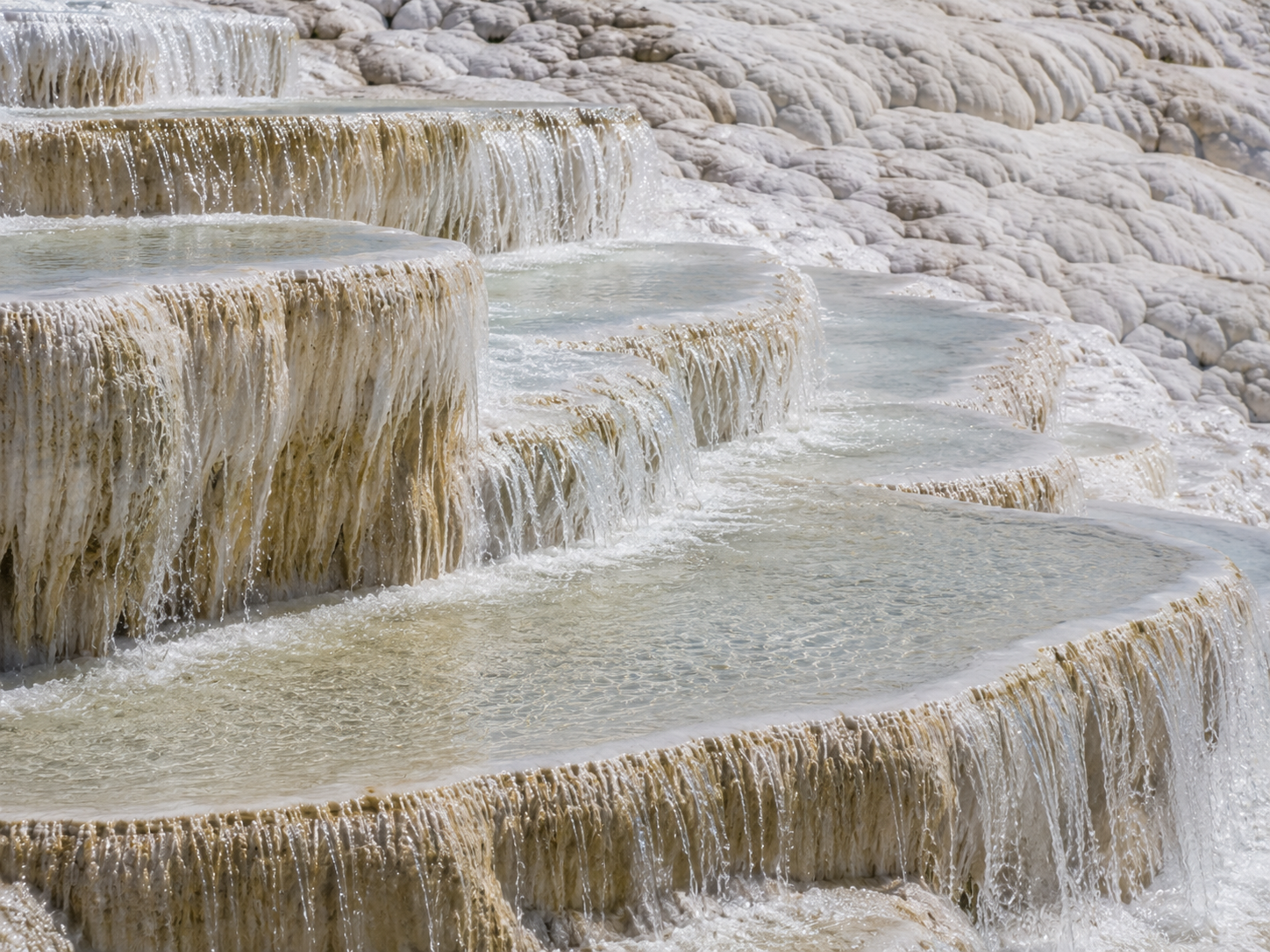 Shallow thermal pools cascade down the stepped travertine terraces of Pamukkale.