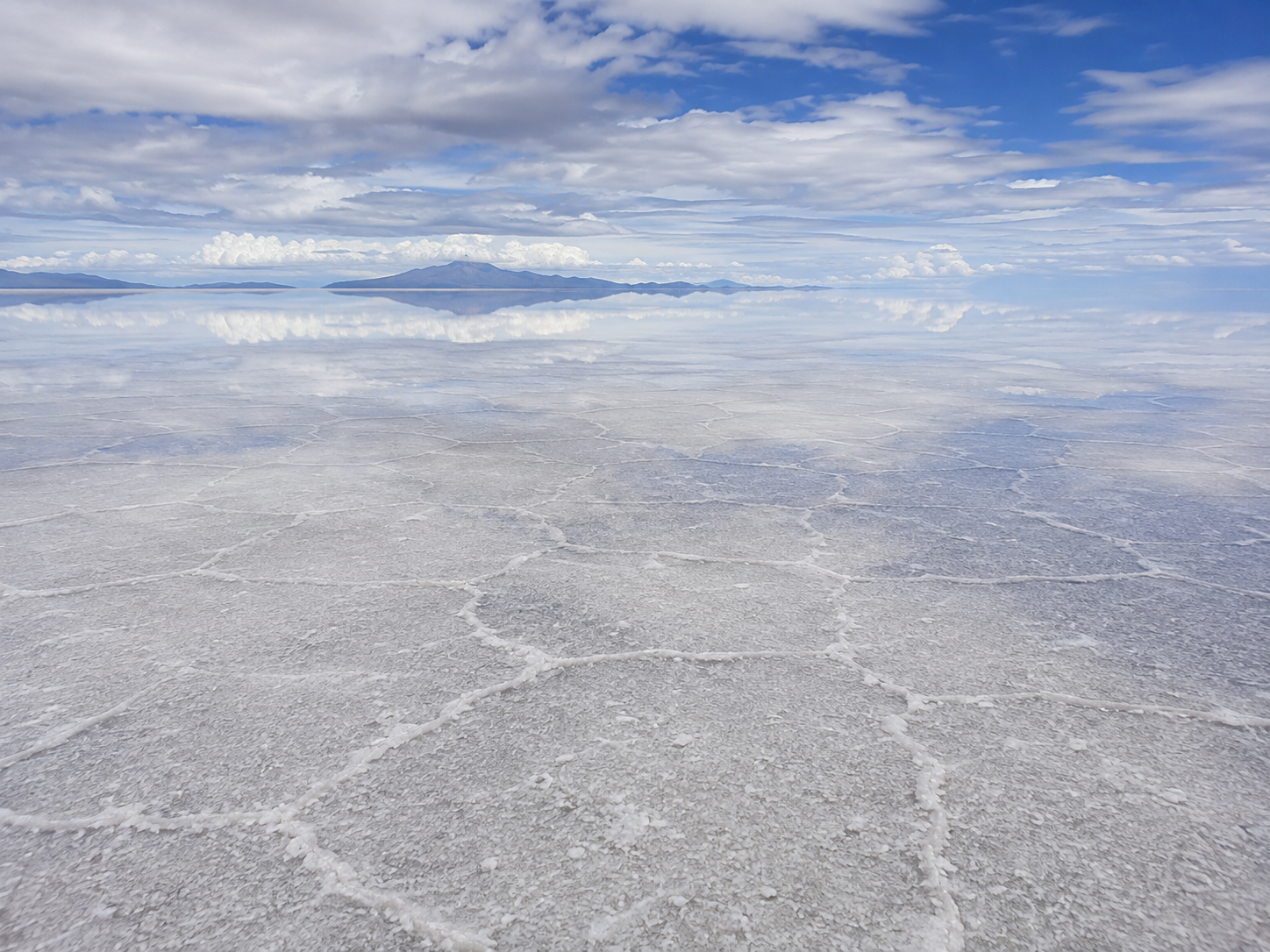 Rainwater forms a thin reflective layer over the salt crust during Salar de Uyuni’s wet season.