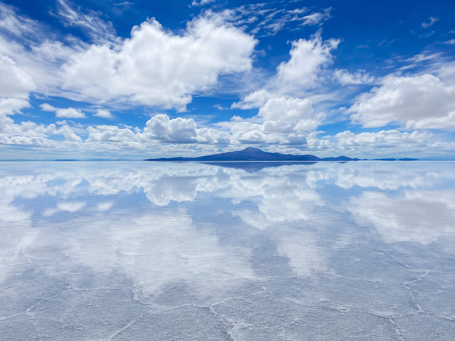 A thin layer of water turns Bolivia’s Salar de Uyuni into a vast mirror reflecting the sky and distant mountains.