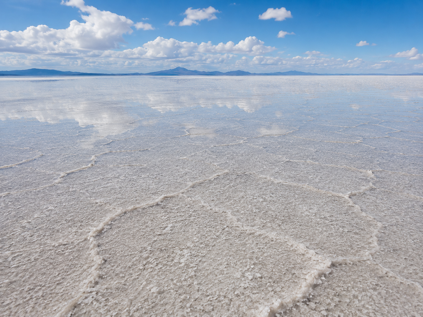 A shallow sheet of water spreads across the exceptionally flat surface of Salar de Uyuni.