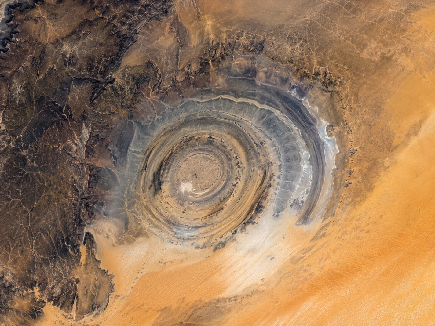The Richat Structure forms enormous concentric rings clearly visible from space in the Sahara Desert of Mauritania.
