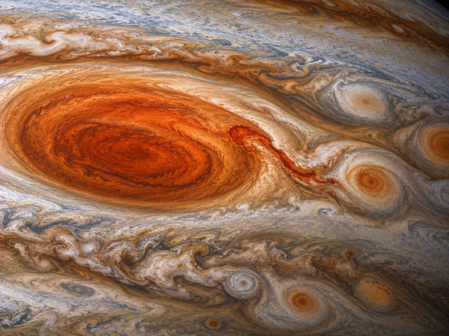 Smaller storms interact with the edge of Jupiter’s Great Red Spot and disturb its outer clouds.
